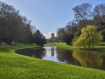 Looking towards Fountains Abbey from the River Skell with the reflection of the tower visible in the water.jpg